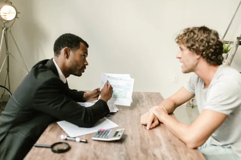 An adviser discussing paperwork with a client at a desk