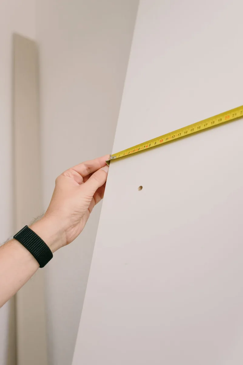 A person measuring a wall inside a property