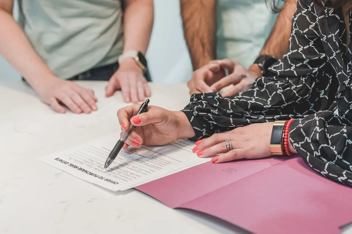 A person signing paperwork at a meeting table